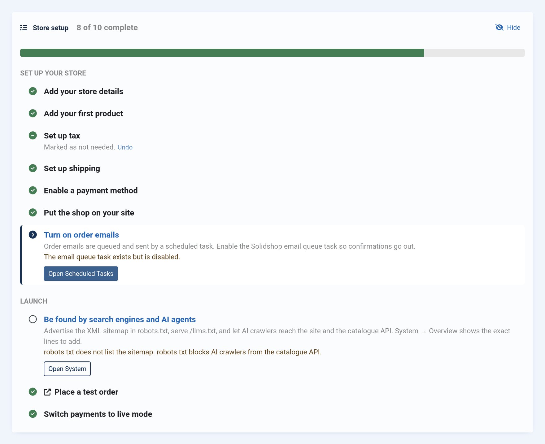The Store setup panel on the Solidshop dashboard reading 8 of 10 complete: store details, first product, shipping, payment method and storefront pages are done, tax is marked as not needed with an Undo link, Turn on order emails is the current step with the note that the email queue task exists but is disabled, and Be found by search engines and AI agents is open with the robots.txt problems it found